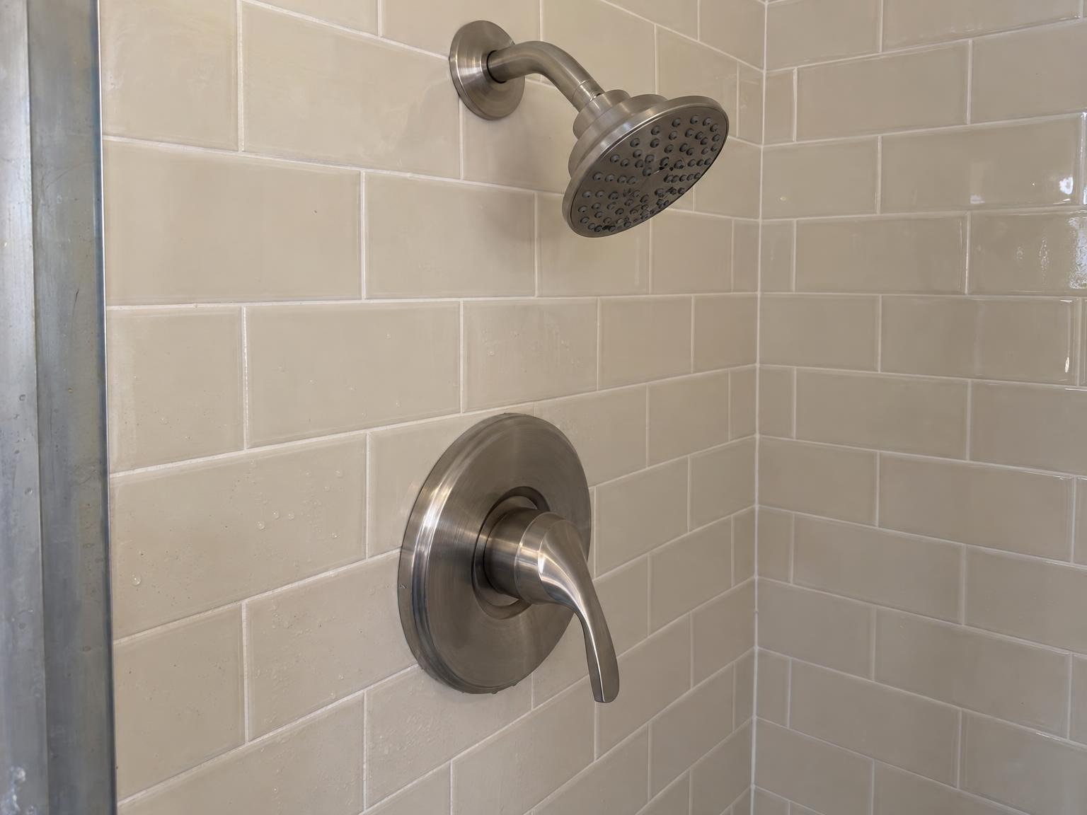 New brushed nickel shower valve and trim on cream subway tile