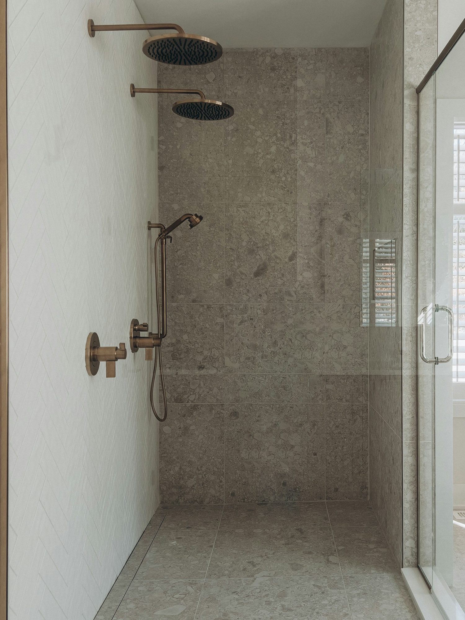 Finished stone-tiled walk-in shower with two rain heads, a handheld and a new valve